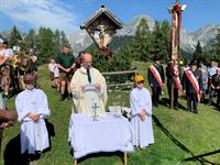 Eine Gruppe von Menschen in Roben, die um einen Tisch mit einem Kreuz darauf stehen